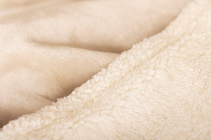 Close-up van de zachte sherpa voering en fluweelachtige bovenlaag van de elektrische warmtedeken van Serenova – voor ultiem comfort en luxe warmte.

