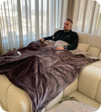 Man ontspant met XXL warmtedeken op de bank – perfect formaat voor één of twee personen.  