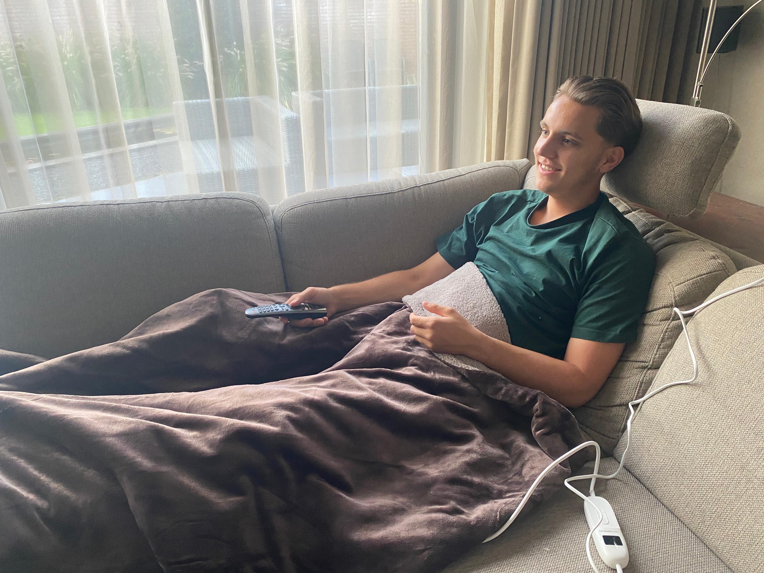 Man ontspannen op de bank met de Serenova elektrische warmtedeken genietend van een rustmoment. 